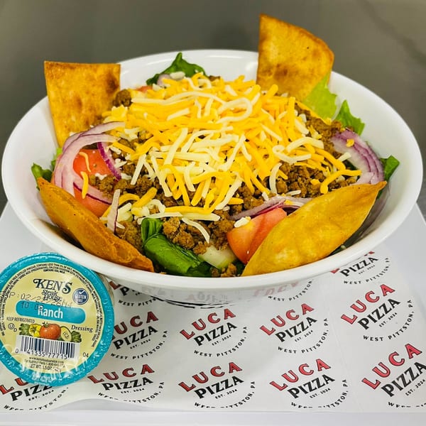 A taco salad with ground beef, shredded cheese, tomatoes, red onions, and tortilla chips.